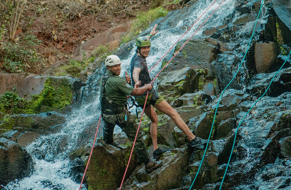 jovem com instrutor escalando cachoeira no Clara Dourado