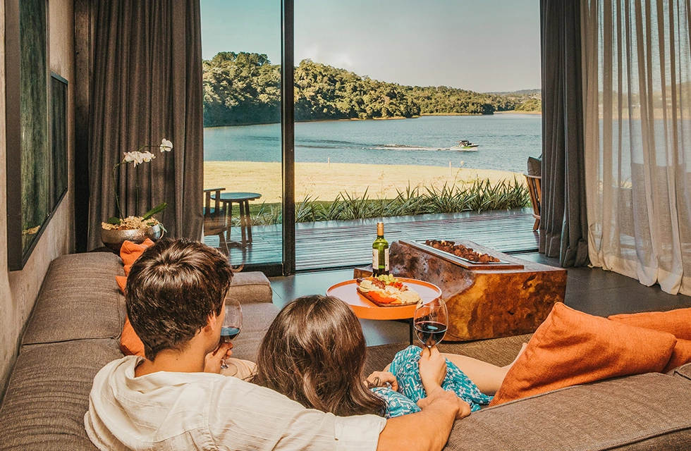 casal tomando vinho e apreciando a paisagem do quarto Clara Ibiúna