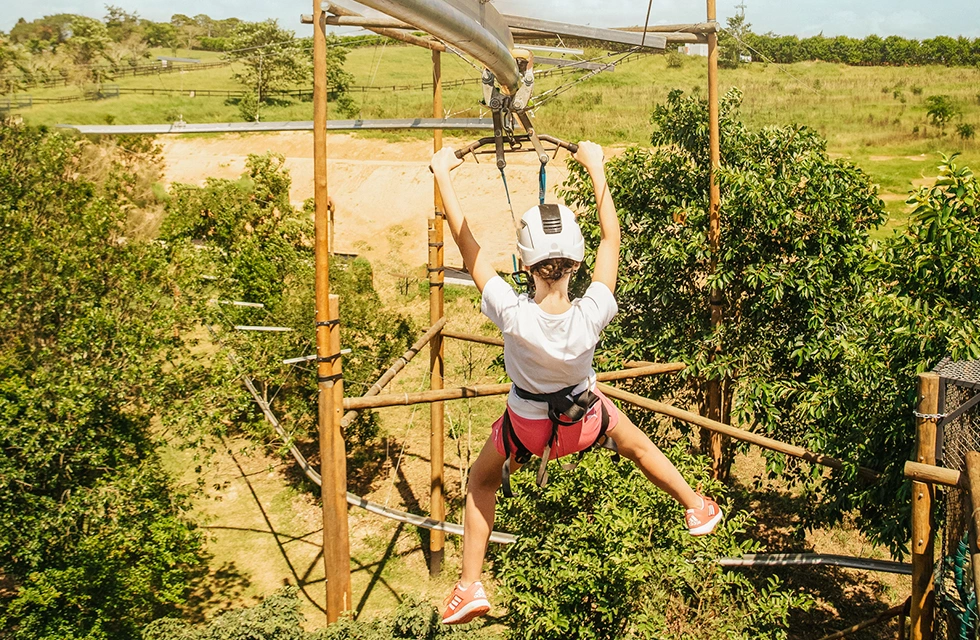 jovem andando de tirolesa em meio a natureza no Clara Ibiúna