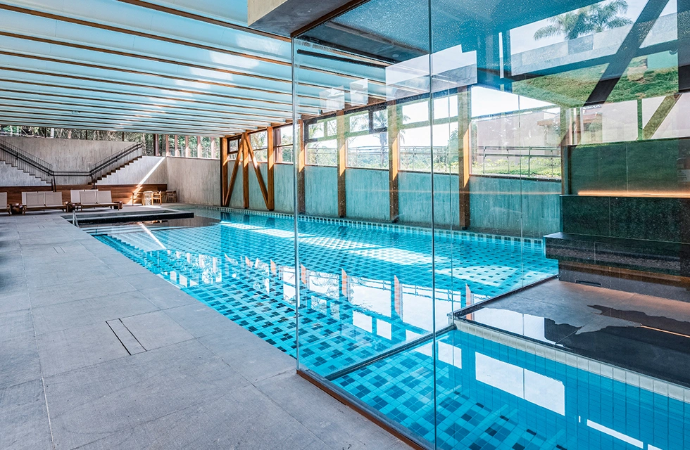 vista lateral da piscina aquecida do Clara Arte, com diversas cadeiras, espaço para adulto e criança, inclusive com sauna disponível